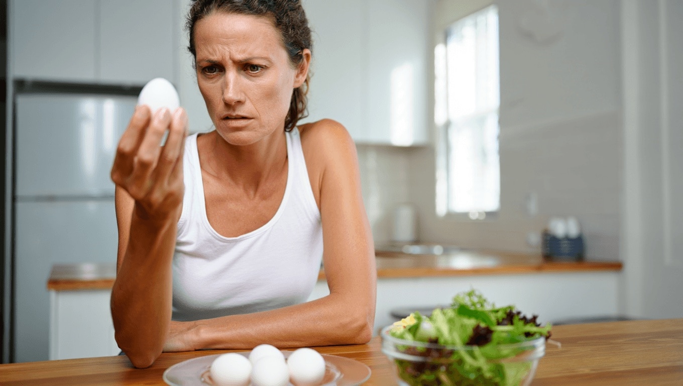 Woman refusing to eat eggs. Egg Free Affected Allergy Banned Restriction. Young beautiful woman holding fresh egg at home with open hand doing stop sign with serious and confident expression