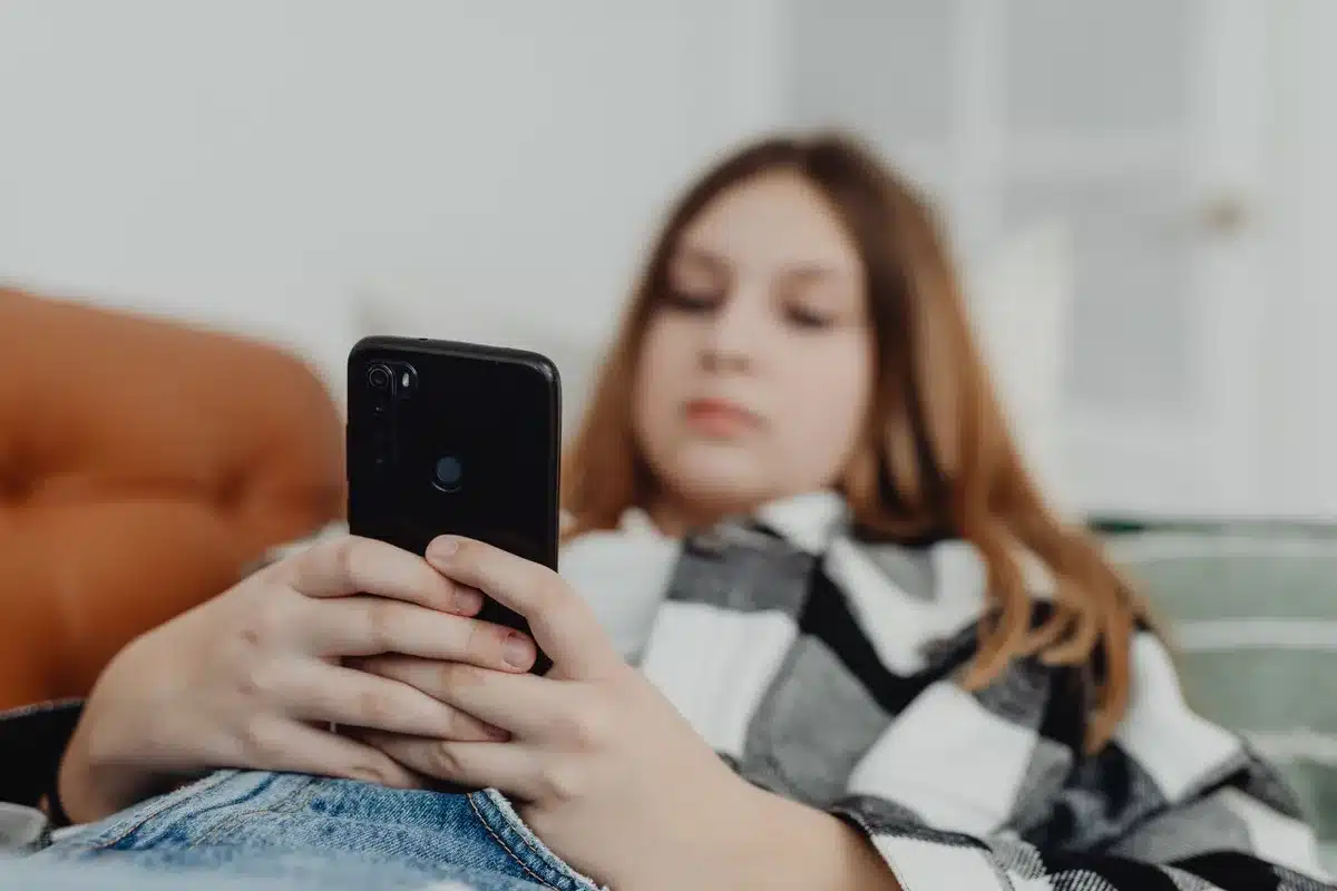 Adolescent consulter les réseaux sociaux sur son téléphone