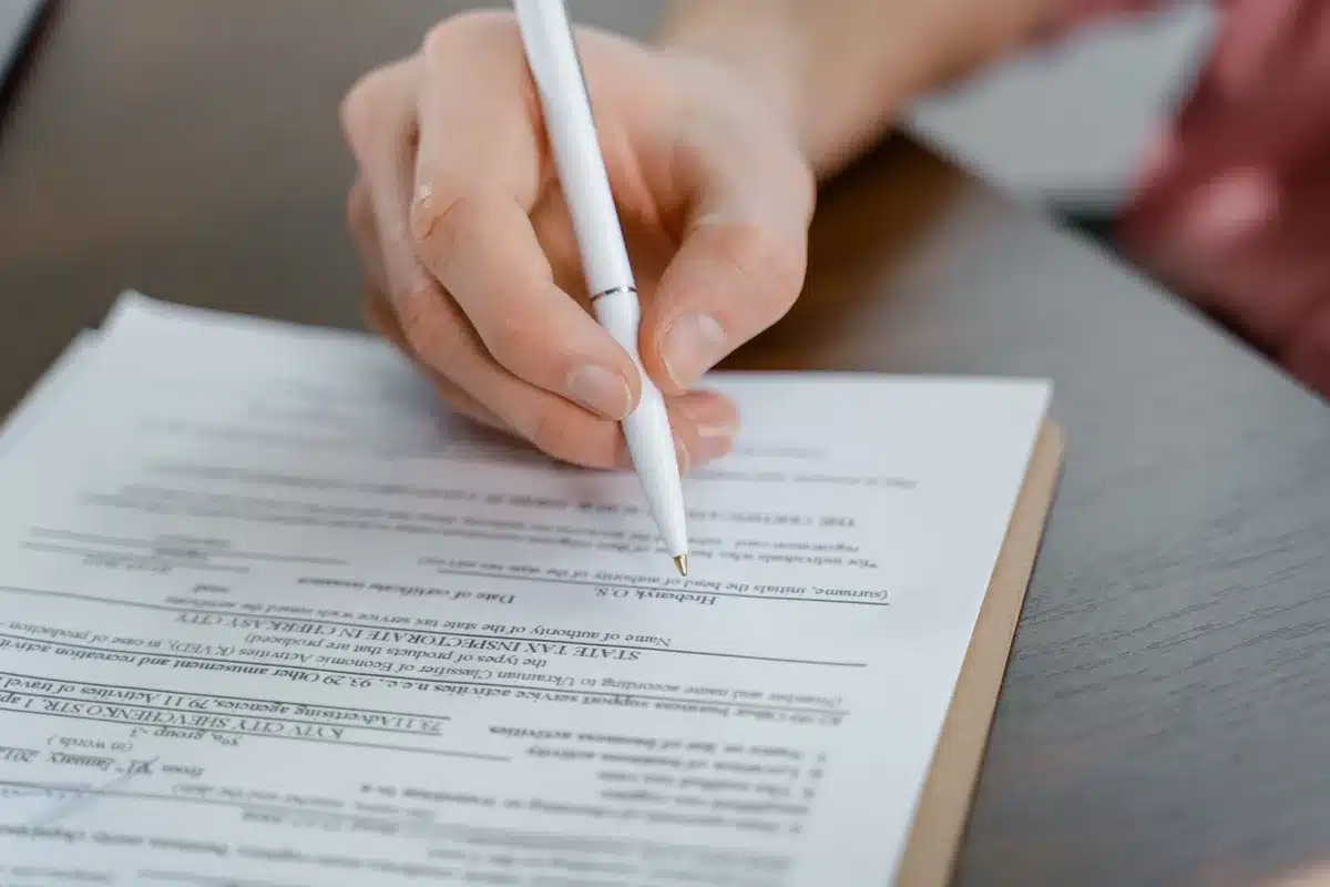Mains anonymes signant un document professionnel sur un bureau en milieu corporatif