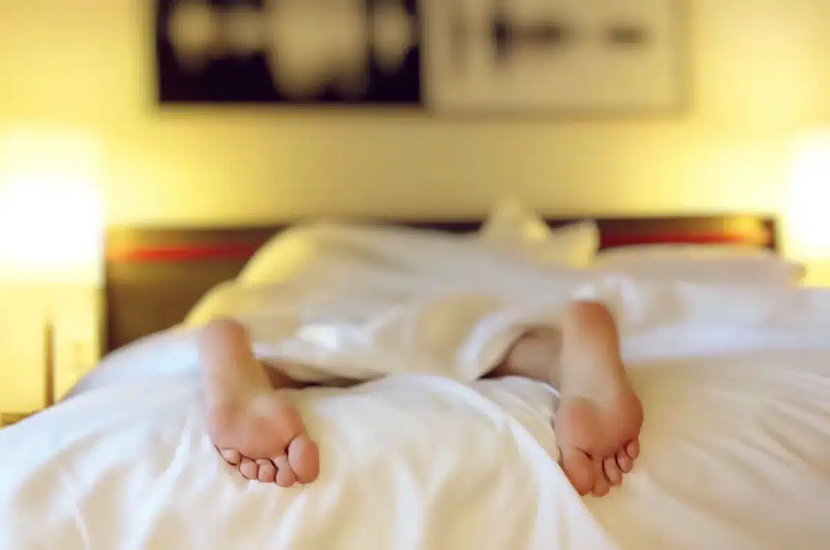 Personne allongée dans un lit sombre, les yeux ouverts, illustrant l'insomnie et les troubles du sommeil