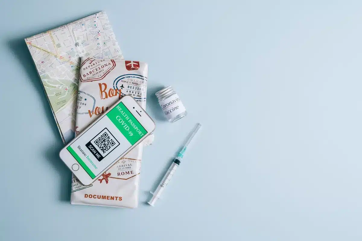 Carte de vaccination, passeport et documents de voyage sur un bureau avec seringue médicale