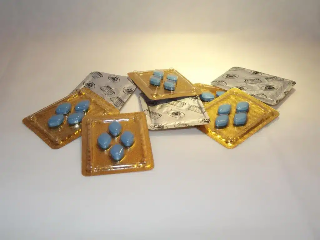 Personne tenant un blister de médicaments avec dossiers médicaux en arrière-plan