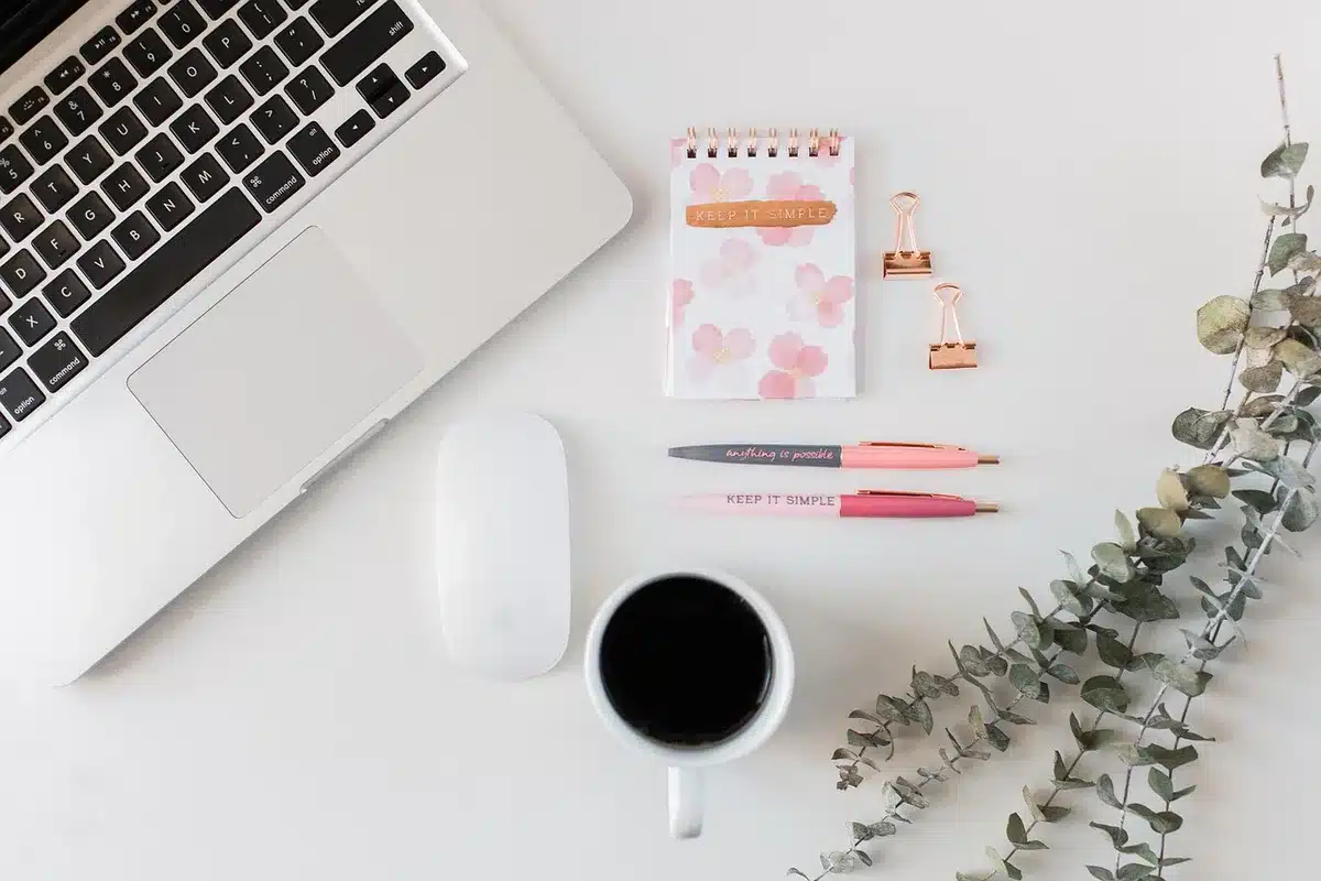 Bureau lumineux près d'une fenêtre avec carnet, ordinateur fermé et tasse
