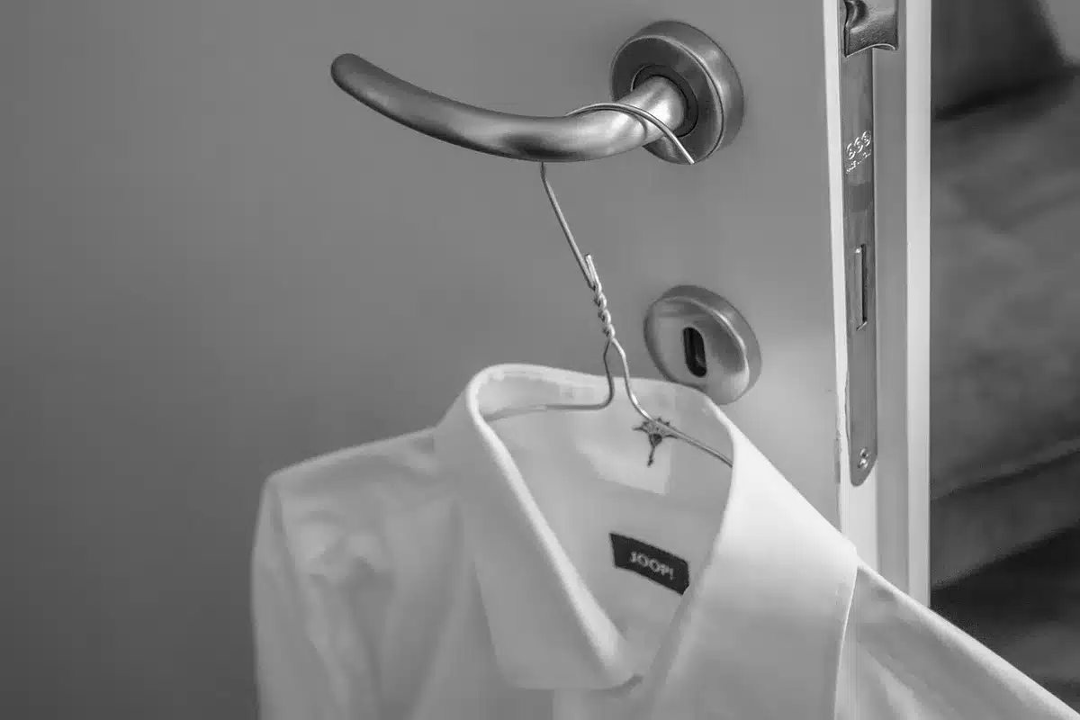 Personne choisissant une tenue blanche devant un miroir inondé de lumière du jour