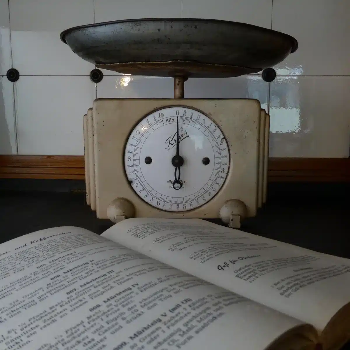 Main tenant une portion de chocolat pesée sur une balance de cuisine