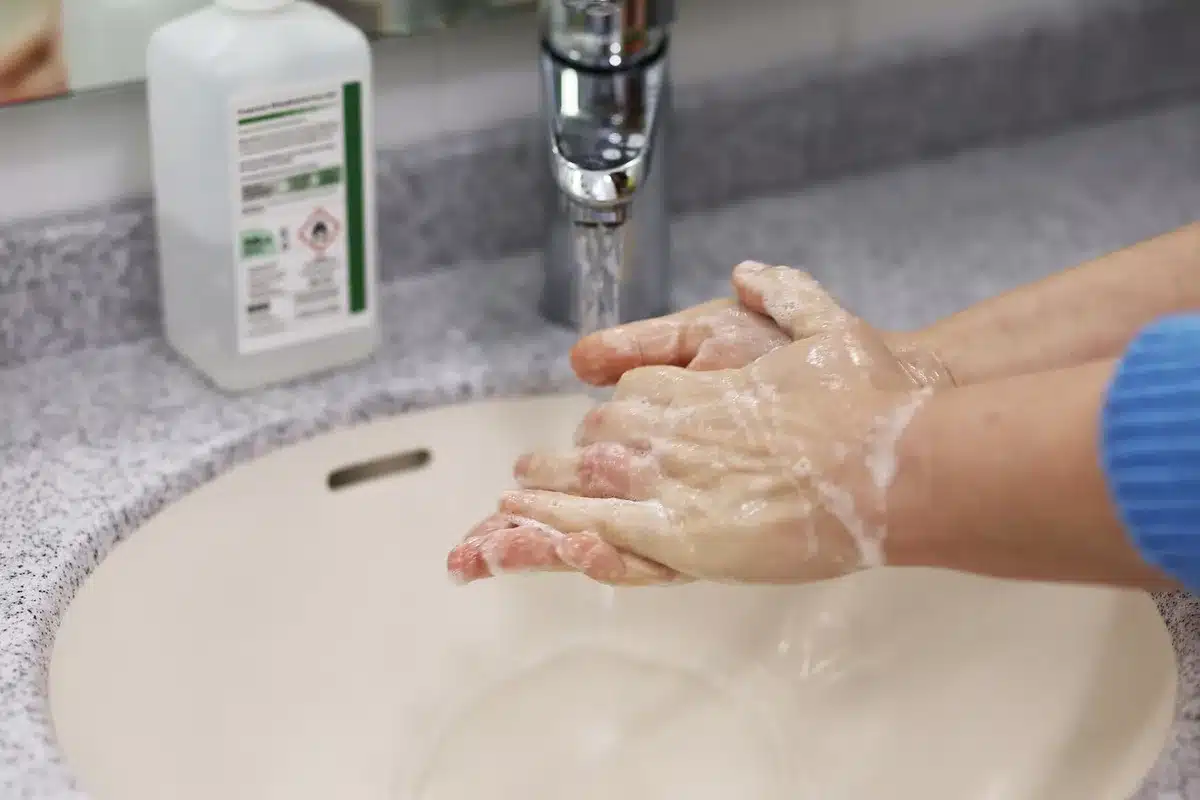 Personne se rinçant le visage à l'eau froide au lavabo