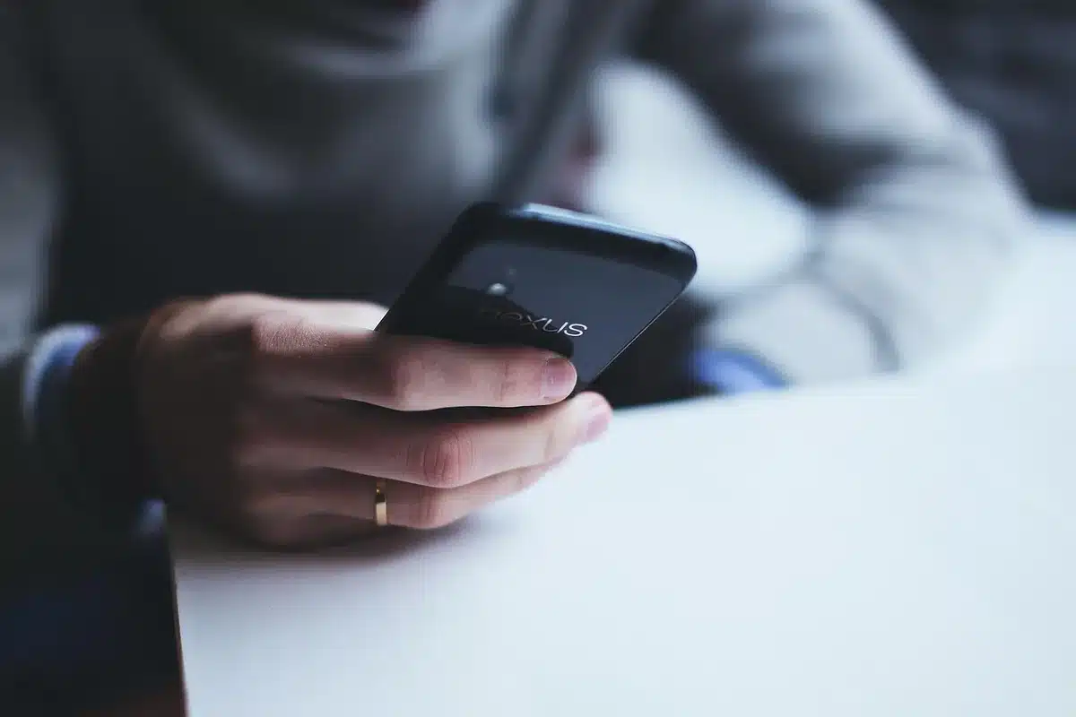 Main écrivant un court message sur un smartphone