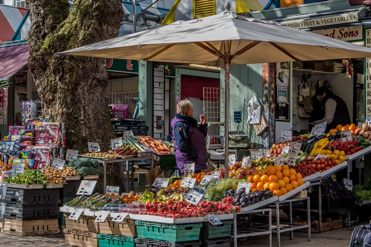 Étal de légumes au marché avec cagettes et étiquettes de prix floues