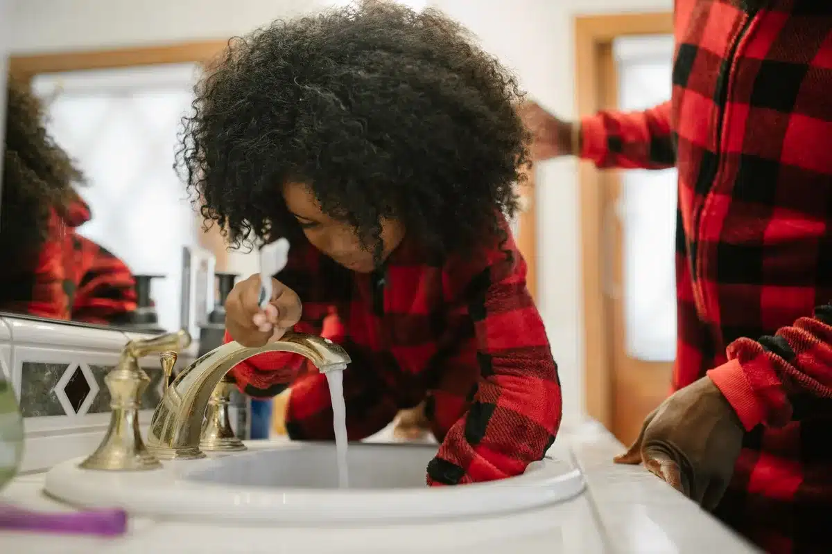 Personne rinçant la bouche à l'eau près d'un lavabo, brosse à dents en vue