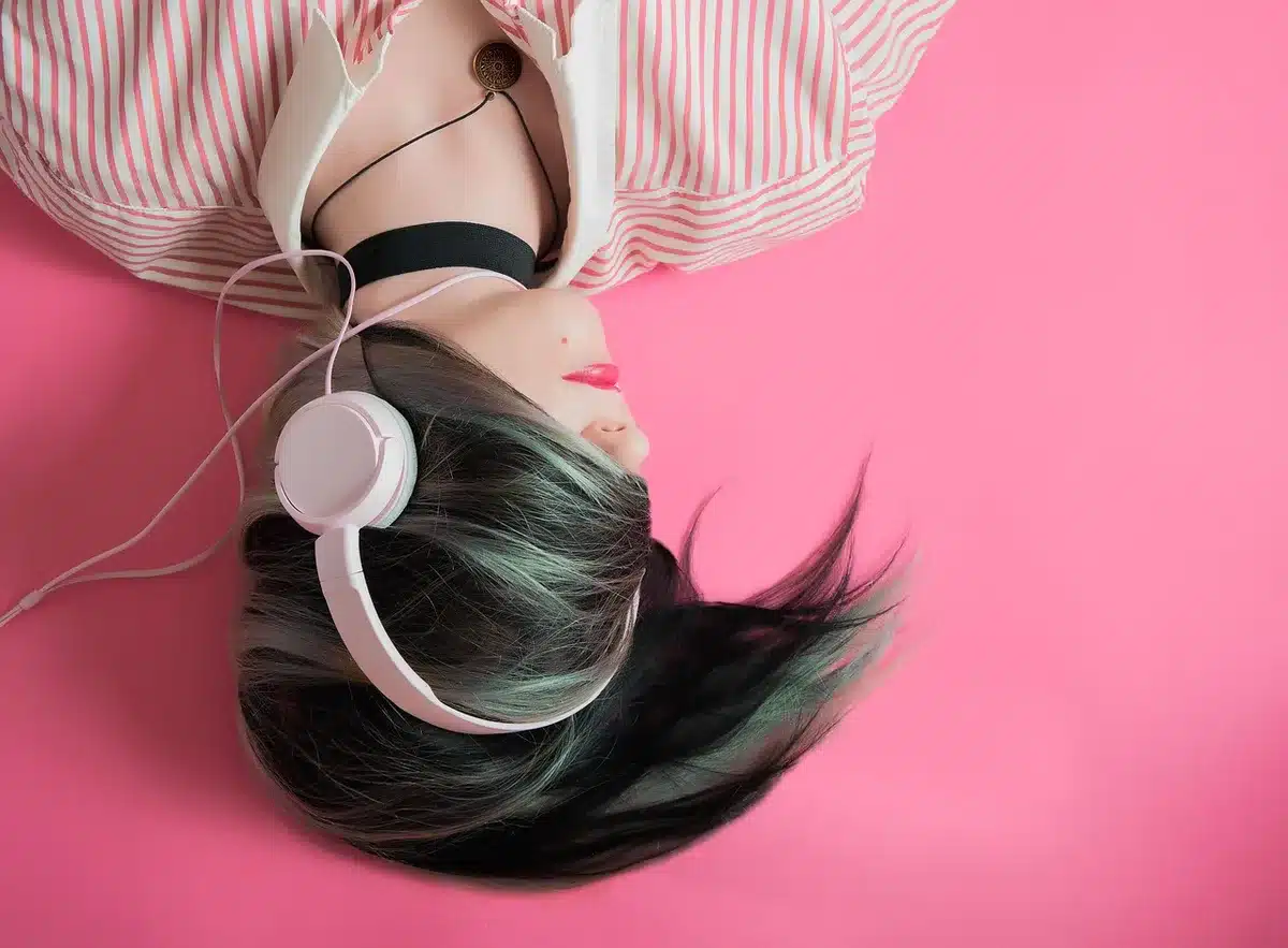 Personne assise près d'une fenêtre, écoute de la musique avec des écouteurs, yeux fermés